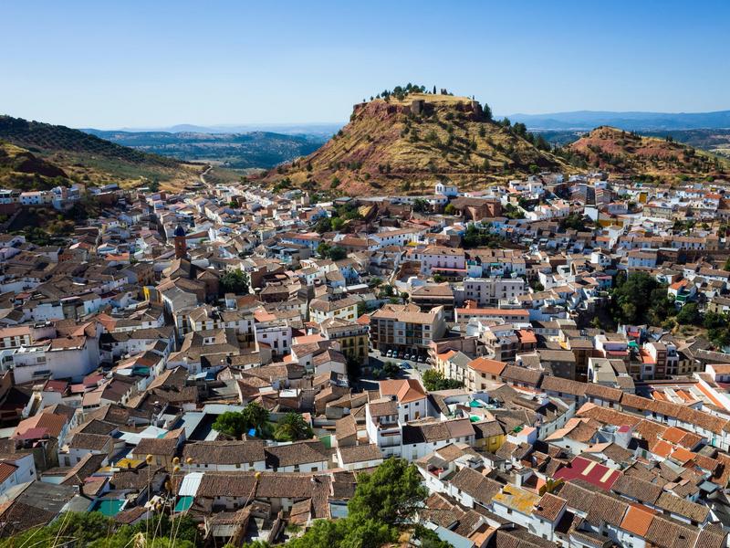 A white town spilling below its castle-topped hill in El Condado, Jaén — explore hilltop history with Andaluciatours.