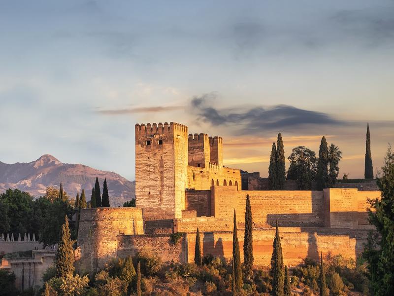 The Alhambra glowing at sunset above Granada with the Sierra Nevada behind, a highlight of Andalucía tours | Andaluciatours