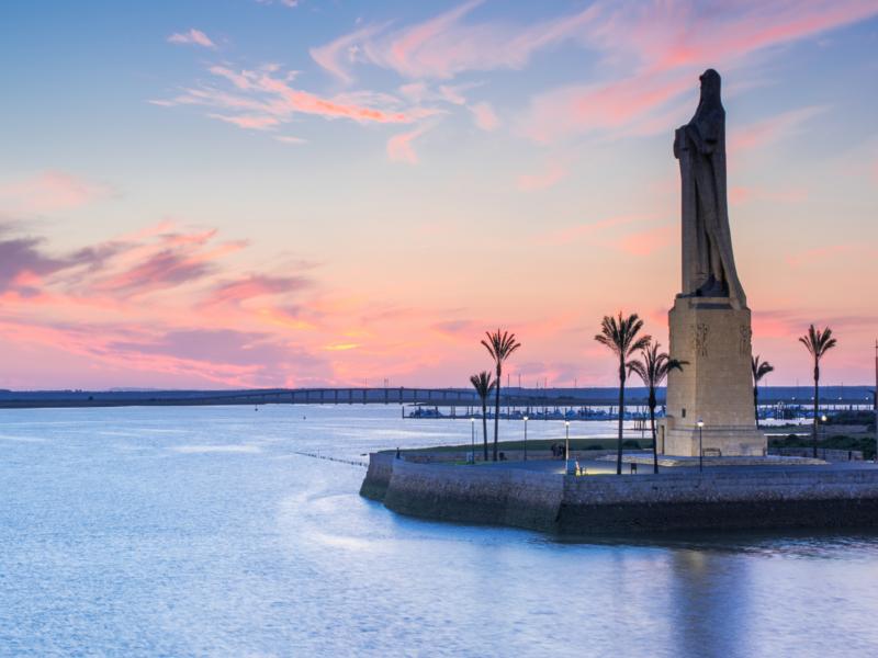 Statue, waterfront, sunset – Huelva, Andalucía | Andaluciatours