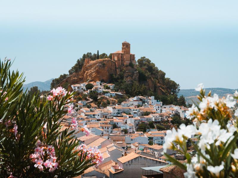 The whitewashed village of Loja rising to its hilltop fortress, framed by oleander, Granada — visit with Andaluciatours.