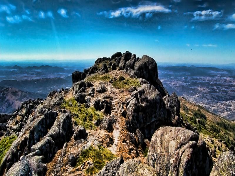 A rocky summit with sweeping panoramic views over the Sierra Norte of Seville — hike the heights with Andaluciatours.